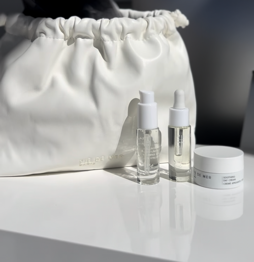 Cosmetic bag with skincare products on a white surface.